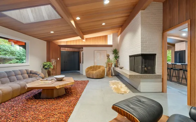 The living room of the renovated 1959 house on SW Laurelwood Avenue: white brick fireplace, exposed beams and a tongue-and-groove ceiling.
